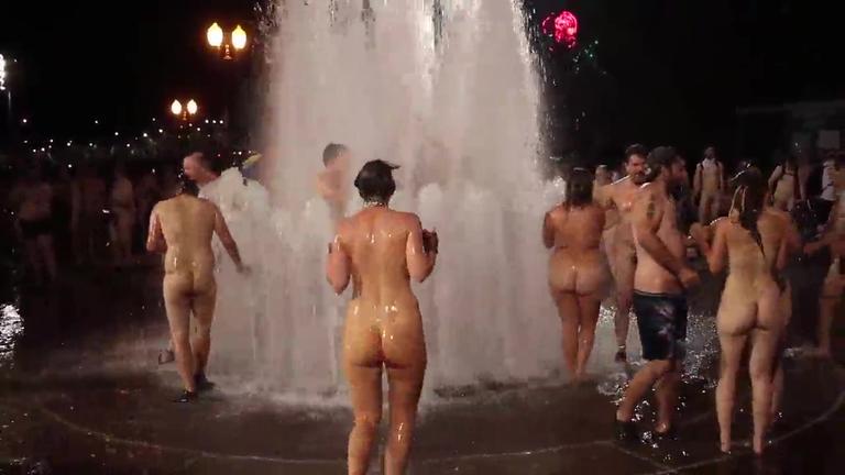 Group of real strangers having fun naked in public fountain